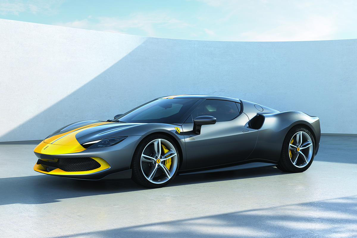 Full side view of yellow and dark gray Ferrari 296 GTB parked in front of a white wall